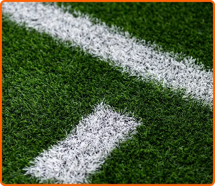 Gros plan détaillé des marquages blancs sur de l'herbe artificielle verte, symbolisant les terrains de rugby professionnels, la compétition sportive et la stratégie de jeu.